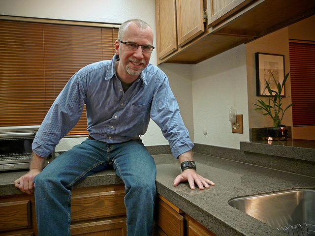 Smiling man sits in newly renovated kitchen