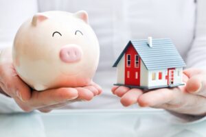 holding piggy bank and model house in hands