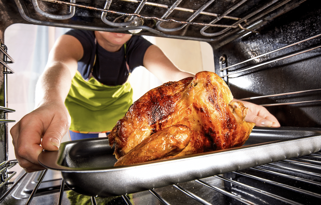 Woman Preparing a Holiday Feast: Placing a Turkey in the Oven
