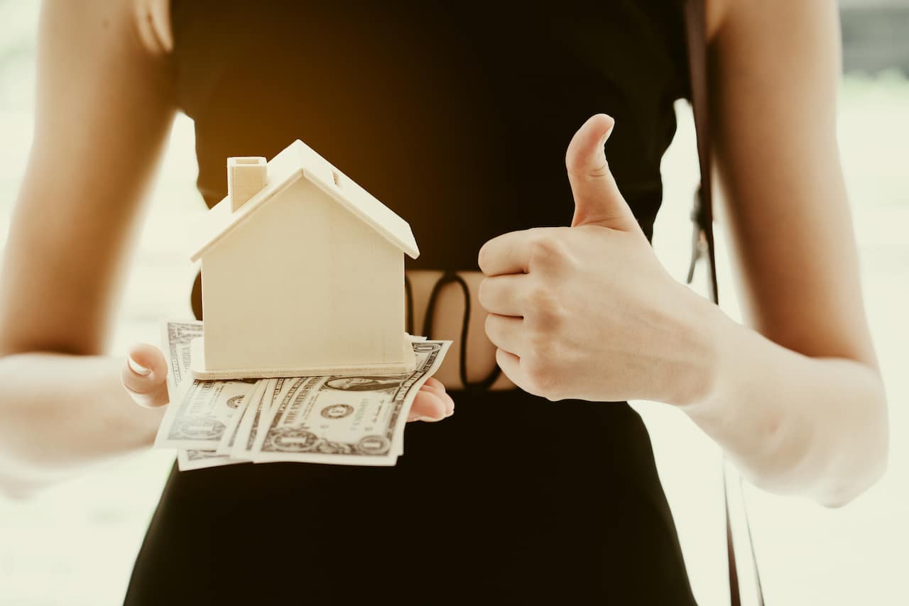 Woman Holding House Model and Money - Home Ownership and Financial Stability