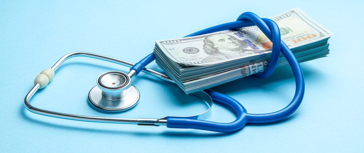 Medical equipment and money on a blue background, signifying the financial burden of medical debt