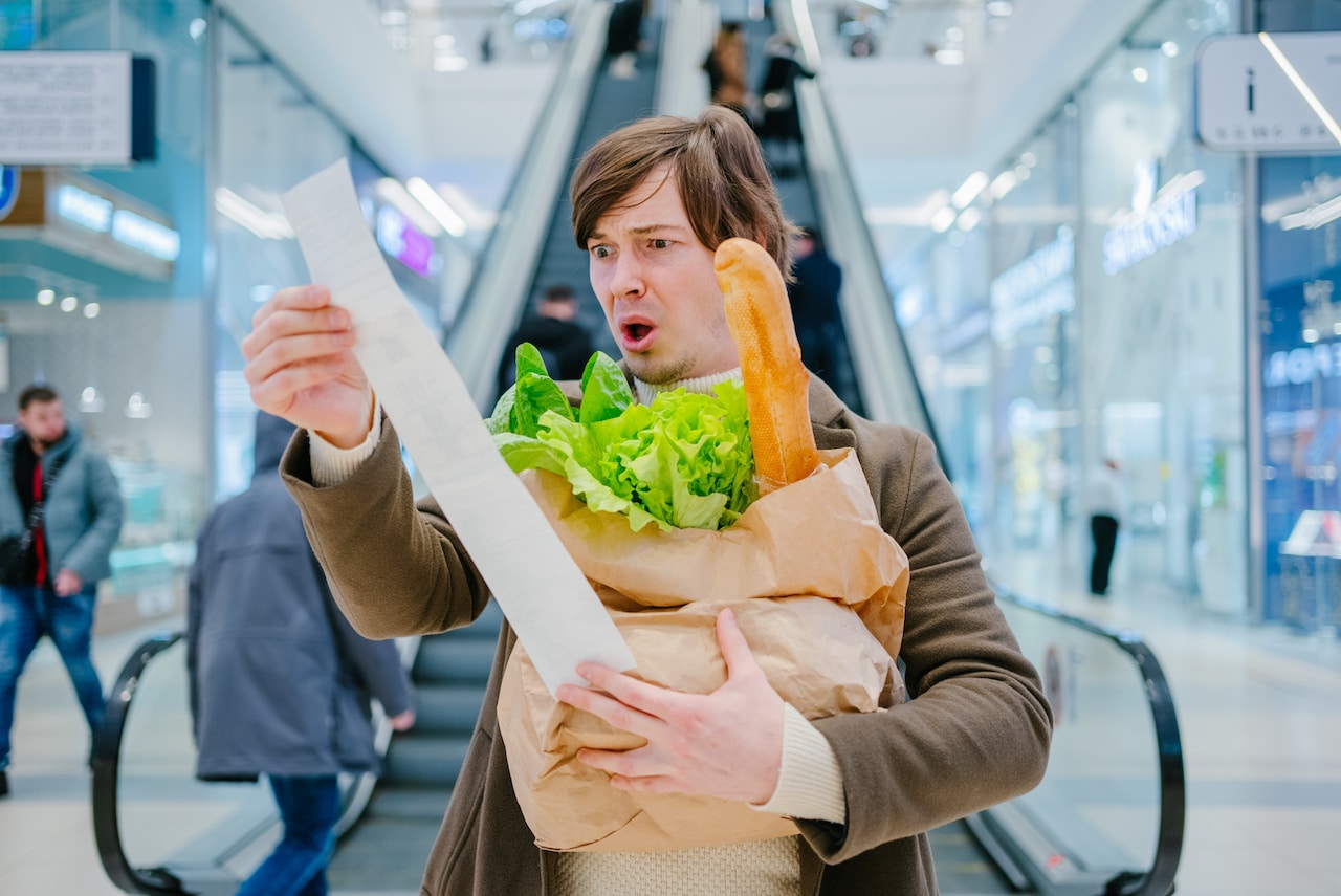 Man with food and belongings, symbolizing the need to adjust spending habits due to inflation.