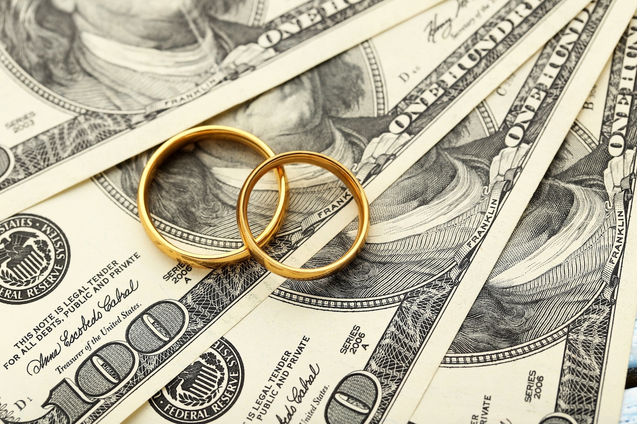 Two Gold Wedding Rings on Dollar Bill Stack